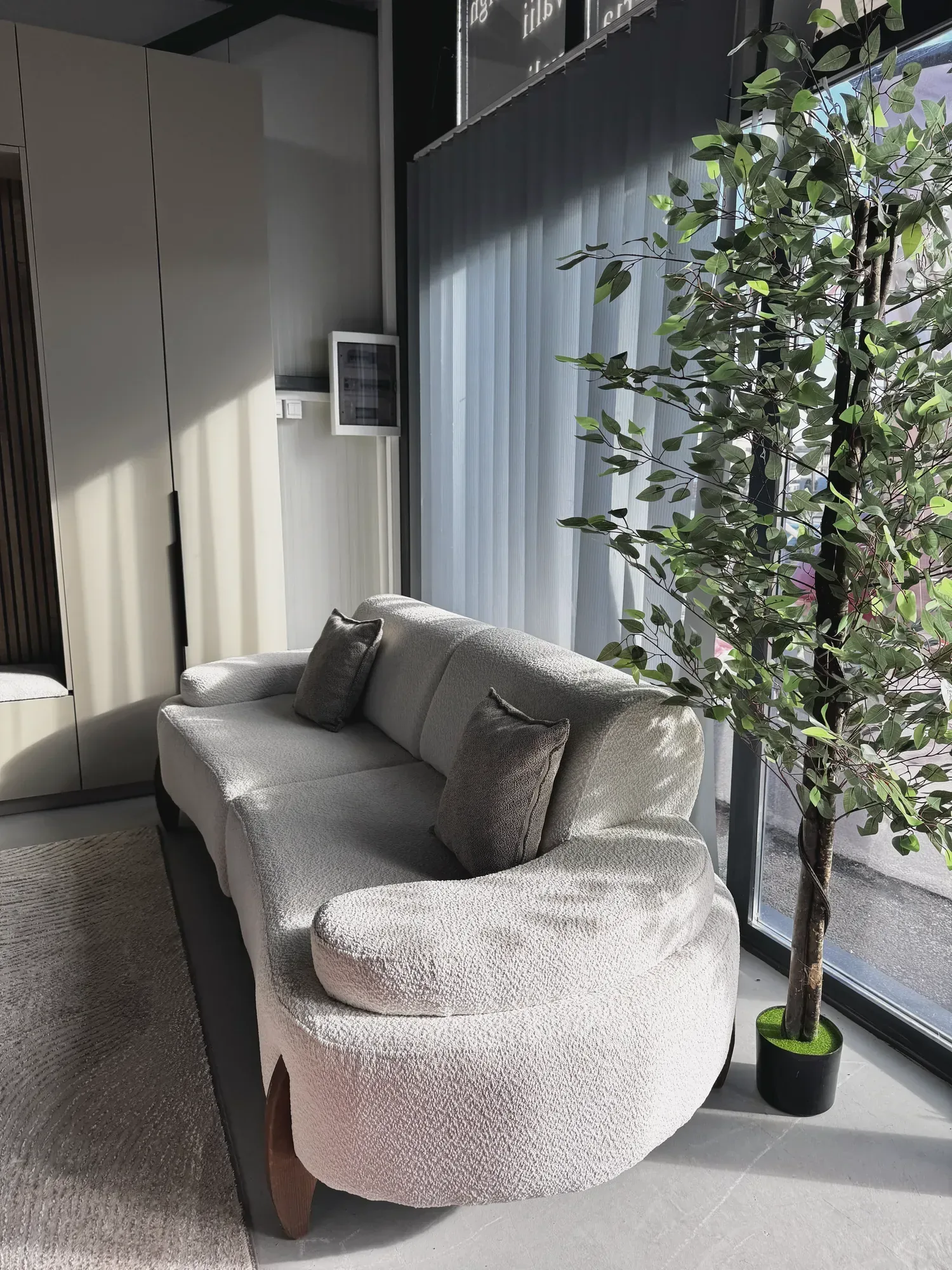 Garniturë e bardhë e lakuar me jastëkë gri në showroom